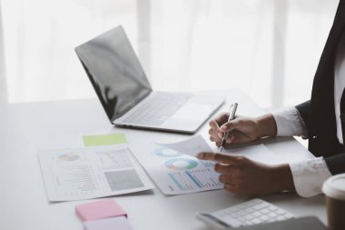A female financier is reviewing company financial documents, monthly financial statement summary from the finance department. The concept of managing the company's finances for accuracy and growth.