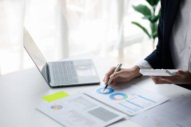 A female financier is reviewing company financial documents, monthly financial statement summary from the finance department. The concept of managing the company's finances for accuracy and growth.