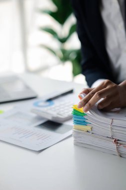 İşadamı masasında yığınla evrak, şirket finans belgeleri ve aylık mali özet kağıtlarını karıştırıyor. Organizasyondaki belge yönetimi kavramı.