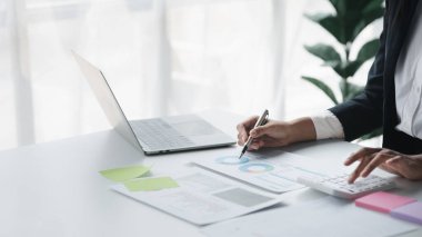 A female financier is reviewing company financial documents, monthly financial statement summary from the finance department. The concept of managing the company's finances for accuracy and growth.