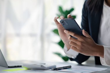 young businesswoman looking at financial information from a mobile phone, she is checking company financial documents, she is a female executive of a startup company. Concept of financial management.