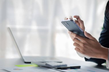 young businesswoman looking at financial information from a mobile phone, she is checking company financial documents, she is a female executive of a startup company. Concept of financial management.