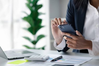 Cep telefonundan mali bilgilere bakan genç bir iş kadını, şirketin mali belgelerini kontrol ediyor, yeni kurulan bir şirketin kadın yöneticisidir. Mali yönetim kavramı.