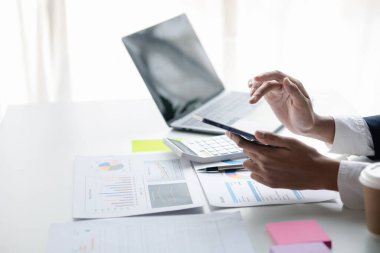 young businesswoman looking at financial information from a mobile phone, she is checking company financial documents, she is a female executive of a startup company. Concept of financial management.