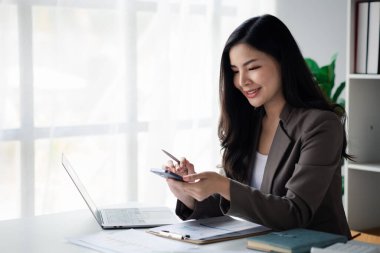 İş kadını verileri görmek için cep telefonunu kullanıyor, genç Asyalı kadınları yönetici olarak görüyor, kurucu yöneticiler ve işletmeciler, genç kadın iş adamları. Girişim iş konsepti.