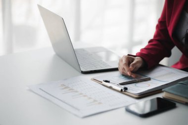 A female financier is reviewing company financial documents, monthly financial statement summary from the finance department. The concept of managing the company's finances for accuracy and growth.