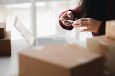 İnsanlar paket kutularının fotoğraflarını çekiyor, çevrimiçi ürünleri satıyor, online alışveriş sitelerinden sipariş veren müşterilerin siparişlerine göre ürünleri paketliyorlar. Ürün çevrimiçi ve e-ticaret satışı.