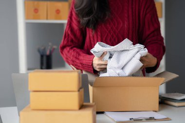 Ürünleri paket kutulara paketlemek, ürünleri çevrimiçi satmak, online alışveriş sitelerinden sipariş veren müşterilerden sipariş almak. Ürün çevrimiçi ve e-ticaret kavramı.