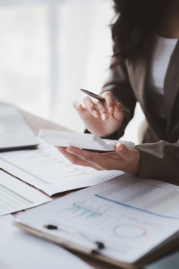 Şirketin mali belgelerindeki rakamları hesaplamak için hesap makinesi kullanan bir işadamı, şirketin nasıl büyüyeceğini planlamak için tarihsel finansal verileri analiz ediyor. Mali konsept.