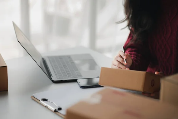 stock image Person writing a customer's address on a parcel box, selling products online, packing orders from customers who order through online shopping sites. Concept of selling products online and e-commerce.