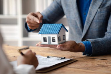 A home rental company employee is handing the house keys to a customer who has agreed to sign a rental contract, explaining the details and terms of the rental. Home and real estate rental ideas.