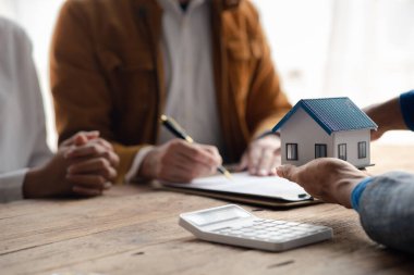 A home rental company employee is handing the house keys to a customer who has agreed to sign a rental contract, explaining the details and terms of the rental. Home and real estate rental ideas.