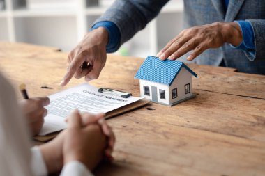 Bir ev kiralama şirketi çalışanı kira sözleşmesi imzalamayı kabul eden bir müşteriye kira sözleşmesinin detaylarını ve şartlarını açıklayan ev anahtarlarını teslim ediyor. Ev ve gayrimenkul kiralama fikirleri.