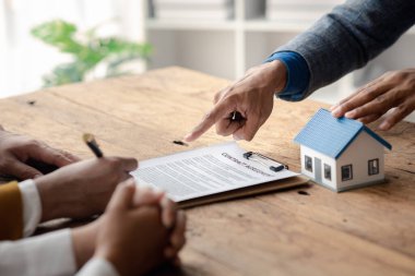 A home rental company employee is handing the house keys to a customer who has agreed to sign a rental contract, explaining the details and terms of the rental. Home and real estate rental ideas.