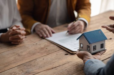 Bir ev kiralama şirketi çalışanı kira sözleşmesi imzalamayı kabul eden bir müşteriye kira sözleşmesinin detaylarını ve şartlarını açıklayan ev anahtarlarını teslim ediyor. Ev ve gayrimenkul kiralama fikirleri.