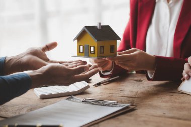 Real estate agents explain models of housing estates in projects to elaborate to clients, explaining and presenting information about homes and purchasing loans. Real estate trading concept.