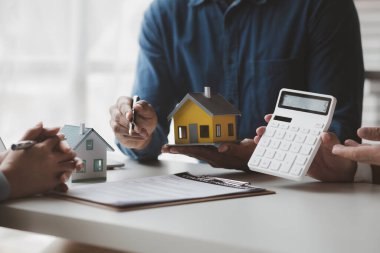 Real estate agents explain models of housing estates in projects to elaborate to clients, explaining and presenting information about homes and purchasing loans. Real estate trading concept.