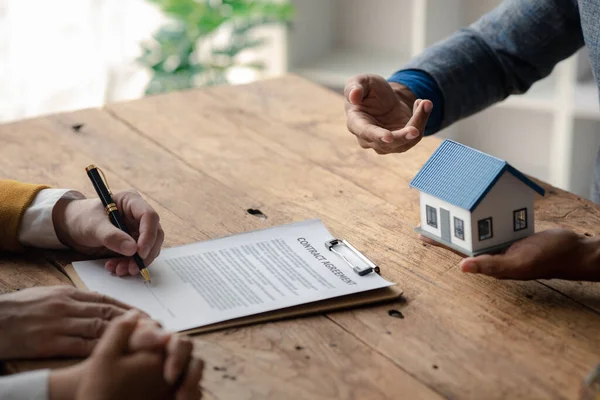 A home rental company employee is handing the house keys to a customer who has agreed to sign a rental contract, explaining the details and terms of the rental. Home and real estate rental ideas.