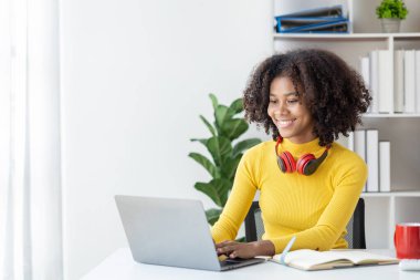 Beyaz odada dizüstü bilgisayarla oturan Amerikalı genç bir kadın. Evde dizüstü bilgisayarla çalışan bir öğrenci. İnternette okuyan bir üniversite öğrencisi..