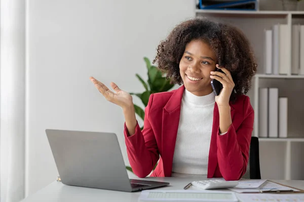 A young American woman is a start-up businesswoman, she sits in her office and talks on the phone with her partner, management and business from a new generation. Startup business management concept.