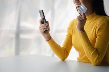 Beautiful woman holding a credit card, she uses a credit card to pay for goods and services online, the concept of using a credit card for online shopping, ordering goods and services on the website.