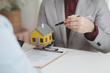 Real estate agents explain models of housing estates in projects to elaborate to clients, explaining and presenting information about homes and purchasing loans. Real estate trading concept.