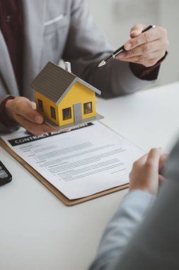 Real estate agents explain models of housing estates in projects to elaborate to clients, explaining and presenting information about homes and purchasing loans. Real estate trading concept.