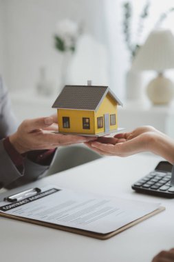 Real estate agents explain models of housing estates in projects to elaborate to clients, explaining and presenting information about homes and purchasing loans. Real estate trading concept.