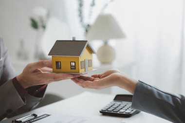 Real estate agents explain models of housing estates in projects to elaborate to clients, explaining and presenting information about homes and purchasing loans. Real estate trading concept.