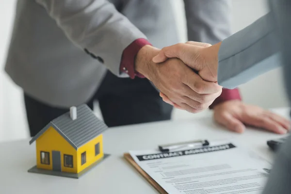 stock image Housing estate agents shake hands with customers after a deal is completed, explaining and presenting information about homes and purchasing loans. Real estate trading concept.