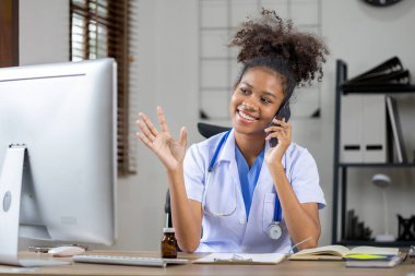 Amerikalı bir kadın doktor telefonda konuşuyor, kendisi pratisyen hekim ve iç hastalıkları tedavi eden bir kadın doktor. Tıbbi konsept ve tedavi.