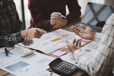 Company meeting room has businessmen and finance managers meeting together on finance topics, they are looking at information on documents and discussing together. Concept company financial management