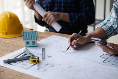 The home design architects are reviewing the house plan draft, the project commissioned by the client, and the custom design before delivery. Interior design and decoration ideas.