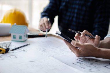 The home design architects are reviewing the house plan draft, the project commissioned by the client, and the custom design before delivery. Interior design and decoration ideas.
