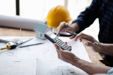 The home design architects are reviewing the house plan draft, the project commissioned by the client, and the custom design before delivery. Interior design and decoration ideas.