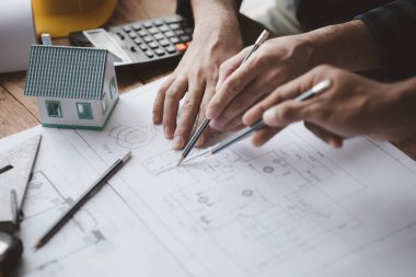 The home design architects are reviewing the house plan draft, the project commissioned by the client, and the custom design before delivery. Interior design and decoration ideas.