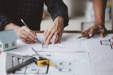 The home design architects are reviewing the house plan draft, the project commissioned by the client, and the custom design before delivery. Interior design and decoration ideas.
