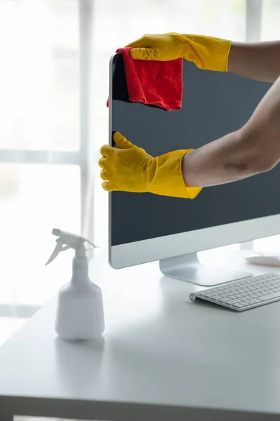 stock image Person cleaning room, cleaning worker is using cloth to wipe computer screen in company office room. Cleaning staff. Concept of cleanliness in the organization.