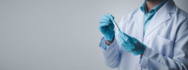Lab assistant, a medical scientist, a chemistry researcher holds a glass tube through the blood sample, does a chemical experiment and examines a patient's blood sample. Medicine and research concept.
