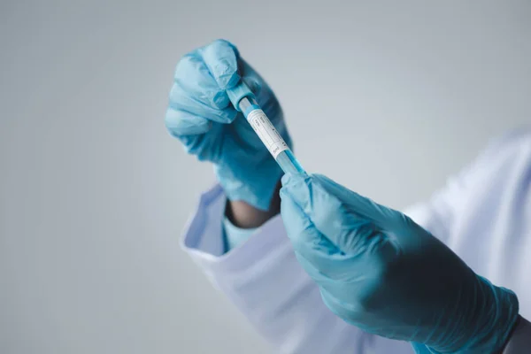 stock image Lab assistant, a medical scientist, a chemistry researcher holds a glass tube through the blood sample, does a chemical experiment and examines a patient's blood sample. Medicine and research concept.