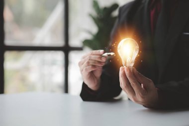 Person holding glowing lamp, Creative new idea. Innovation, brainstorming, strategizing to make the business grow and be profitable. Concept execution, strategy planning and profit management.