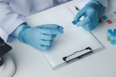 Laboratuvar asistanı, tıp bilimcisi, kimya araştırmacısı kimyasal test tüpünden cam bir tüp tutuyor, kimyasal deney yapıyor ve hastanın örneğini inceliyor. Tıp ve araştırma konsepti.