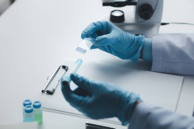 Laboratuvar asistanı, tıp bilimcisi, kimya araştırmacısı kimyasal test tüpünden cam bir tüp tutuyor, kimyasal deney yapıyor ve hastanın örneğini inceliyor. Tıp ve araştırma konsepti.