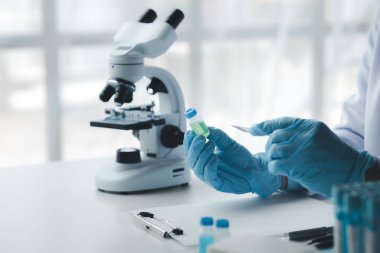 Laboratuvar asistanı, tıp bilimcisi, kimya araştırmacısı kimyasal test tüpünden cam bir tüp tutuyor, kimyasal deney yapıyor ve hastanın örneğini inceliyor. Tıp ve araştırma konsepti.