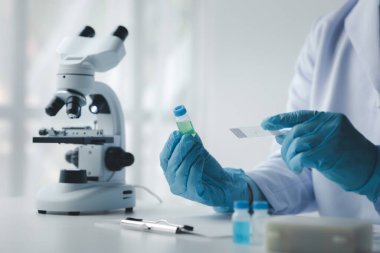 Laboratuvar asistanı, tıp bilimcisi, kimya araştırmacısı kimyasal test tüpünden cam bir tüp tutuyor, kimyasal deney yapıyor ve hastanın örneğini inceliyor. Tıp ve araştırma konsepti.