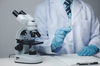 Laboratuvar asistanı, tıp bilimcisi, kimya araştırmacısı kimyasal test tüpünden cam bir tüp tutuyor, kimyasal deney yapıyor ve hastanın örneğini inceliyor. Tıp ve araştırma konsepti.