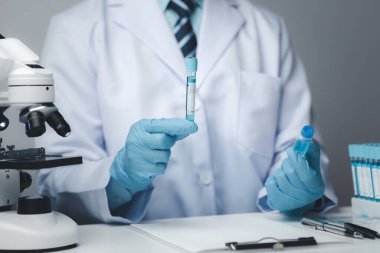 Laboratuvar asistanı, tıp bilimcisi, kimya araştırmacısı kimyasal test tüpünden cam bir tüp tutuyor, kimyasal deney yapıyor ve hastanın örneğini inceliyor. Tıp ve araştırma konsepti.