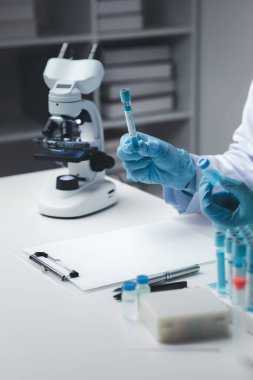Laboratuvar asistanı, tıp bilimcisi, kimya araştırmacısı kimyasal test tüpünden cam bir tüp tutuyor, kimyasal deney yapıyor ve hastanın örneğini inceliyor. Tıp ve araştırma konsepti.