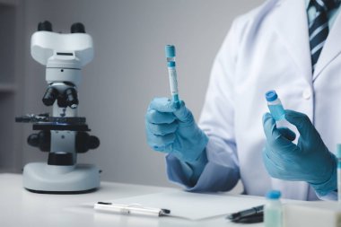 Laboratuvar asistanı, tıp bilimcisi, kimya araştırmacısı kimyasal test tüpünden cam bir tüp tutuyor, kimyasal deney yapıyor ve hastanın örneğini inceliyor. Tıp ve araştırma konsepti.