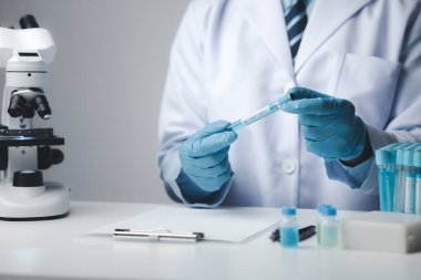 Laboratuvar asistanı, tıp bilimcisi, kimya araştırmacısı kimyasal test tüpünden cam bir tüp tutuyor, kimyasal deney yapıyor ve hastanın örneğini inceliyor. Tıp ve araştırma konsepti.